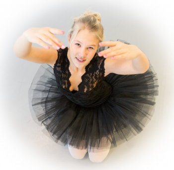 A girl in a ballet skirt with her hands up